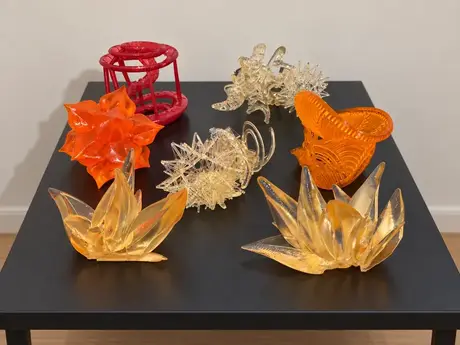Printed sculpture studies grouped on a table, in orange, red and amber resin