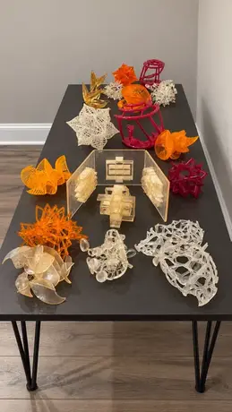 A long table covered with printed sculpture studies, dozens of versions side by side