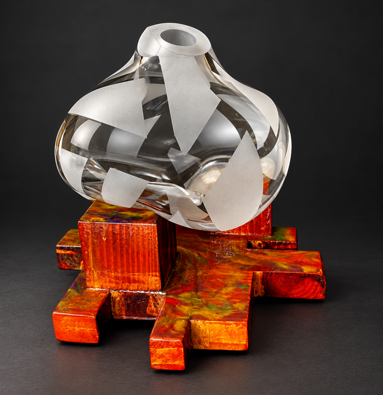 Frosted and clear blown glass vessel resting on an orange resin and wood base