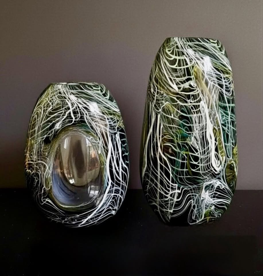 Two dark glass vessels threaded with fine white and green lines
